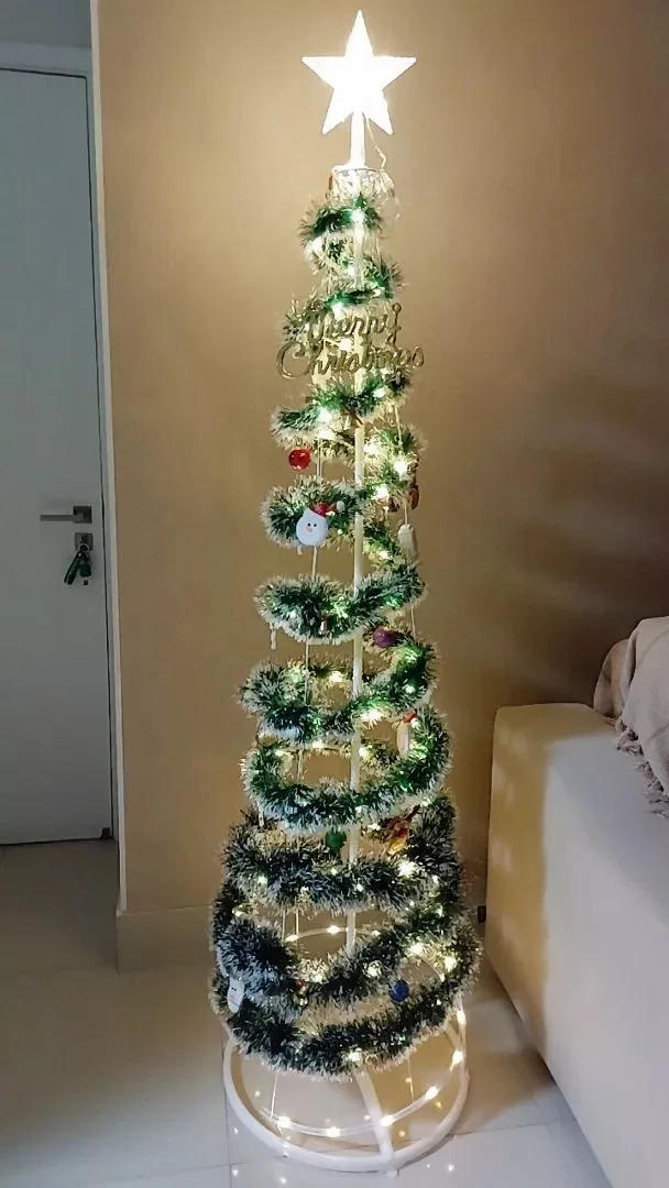 Árvore espiral com festão verde e luzes em uma sala