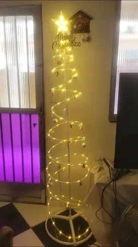 Árvore espiral acesa com luz quente ao lado da janela